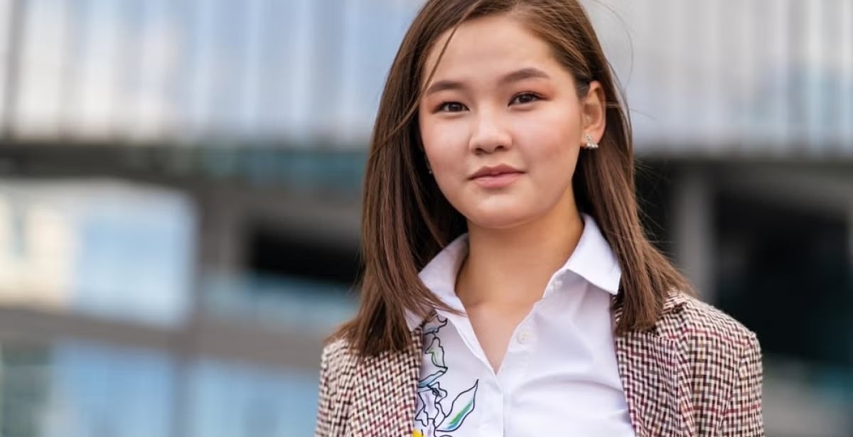 A female diplomat standing confidently outside a modern building.