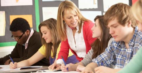 A teacher providing individual support to students working in a classroom environment.